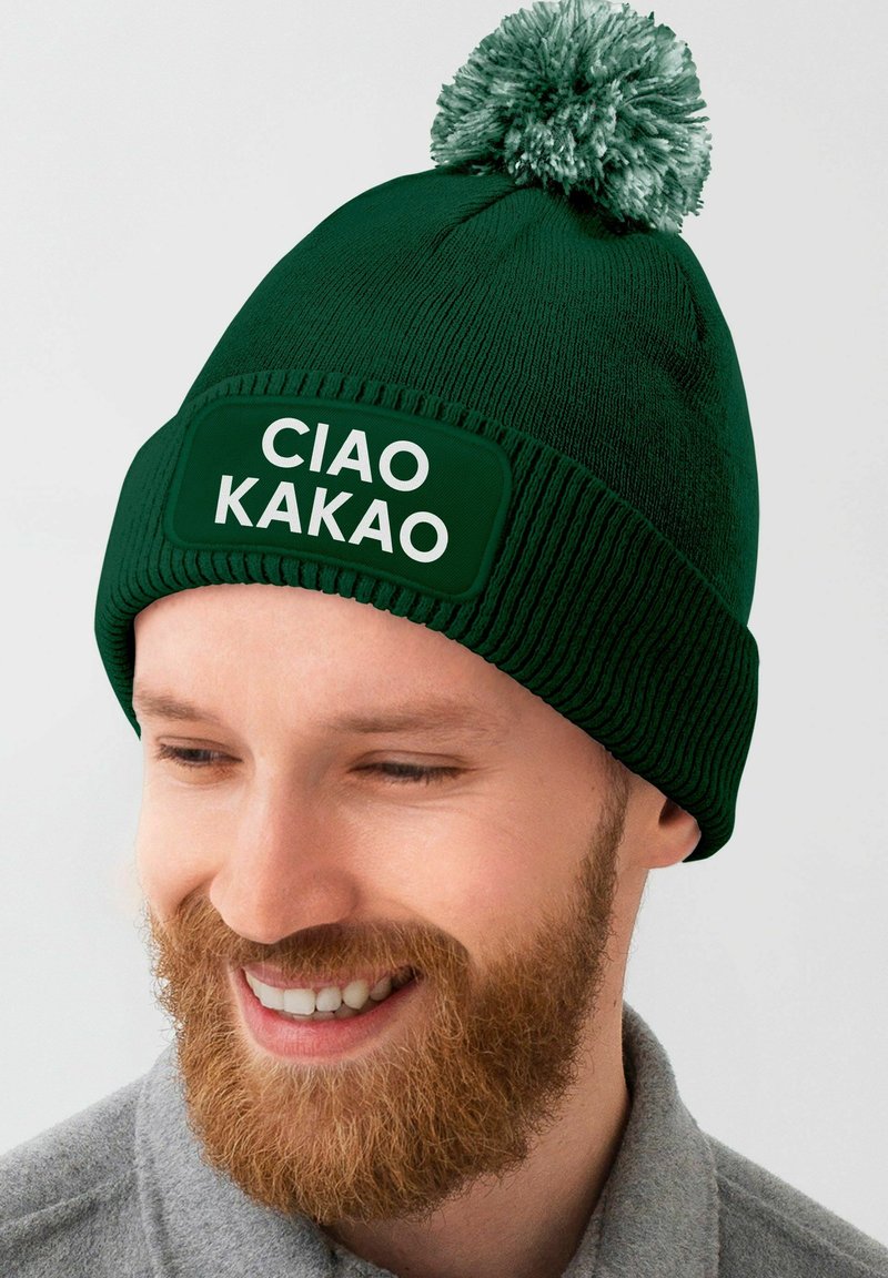 Green knit beanie with a pom-pom, featuring a textured band and a rectangular patch with "CIAO KAKAO" in white lettering.