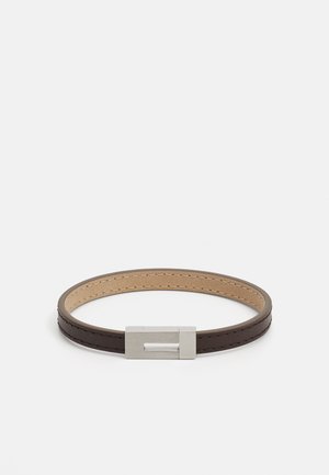 Bruine leren armband met een gladde textuur, voorzien van een rechthoekige zilveren metalen sluiting en contrasterende stiksels langs de randen.