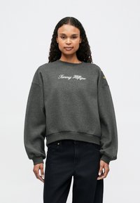 Graue Sweatshirts mit lockerer Passform, gerippten Bündchen und Saum. Mit gesticktem "Tommy Hilfiger"-Logo auf der Vorderseite und Akzentknöpfen an den Ärmeln.