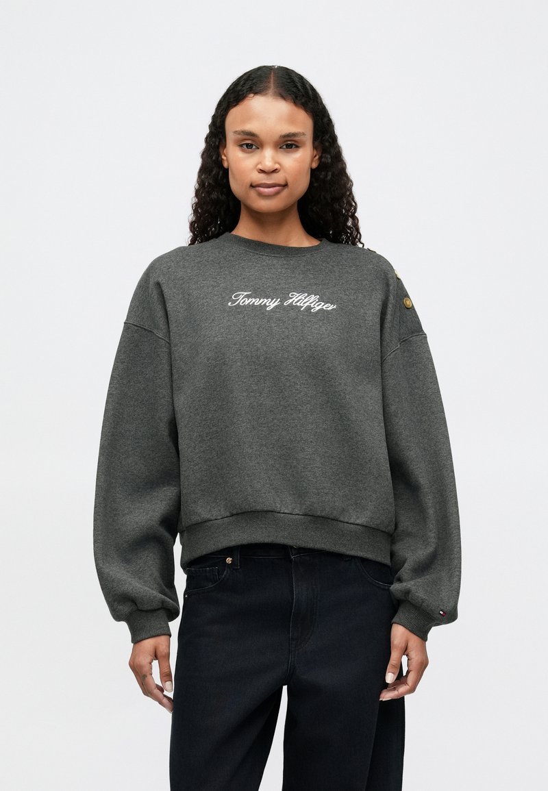 Graue Sweatshirts mit lockerer Passform, gerippten Bündchen und Saum. Mit gesticktem "Tommy Hilfiger"-Logo auf der Vorderseite und Akzentknöpfen an den Ärmeln.
