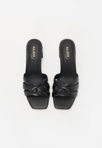 Schwarze Rutschen-Sandalen mit quadratischer Zehenform und verschlungenem Riemendesign. Aus glattem Leder mit matter Oberfläche gefertigt. Markenlogo in Gold aufgedruckt.
