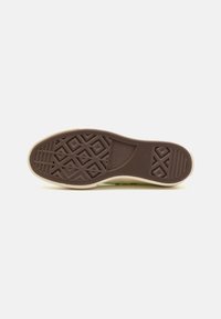 Gummisohle von Sneakers mit komplexen Traktionsmustern. Helles Beige mit einer dunkelbraunen strukturierten Unterseite. Strapazierfähiges und flexibles Design.