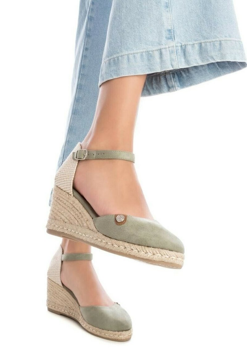 Zapatos de cuña verdes de ante con suela de cuerda de yute, correa en el tobillo y detalle decorativo en los dedos. Acentos tejidos beige en el tacón.
