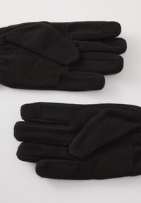 Gants en polaire noire présentant une paume texturée et un motif en losange au niveau des poignets, avec des coutures légèrement surélevées et une finition douce.