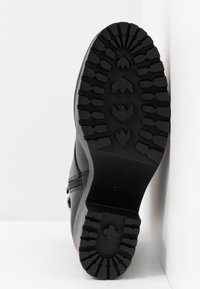 Zwarte rubberen laars met een robuuste rubberen zool, voorzien van een stevig profiel met diepe groeven en verhoogde accentlijnen. Maat aangeduid als 37. Glad bovenleer zichtbaar.