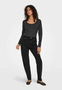 Zwarte lange mouwen top met een ronde hals, gecombineerd met hoge taille zwarte jeans. De jeans hebben voorzakken en subtiele hardware-accenten.