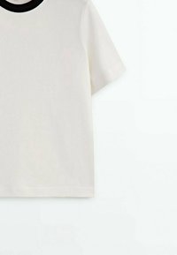 T-shirt blanc à manches courtes avec un col rond noir, présenté de la poitrine vers le bas sur un fond blanc.