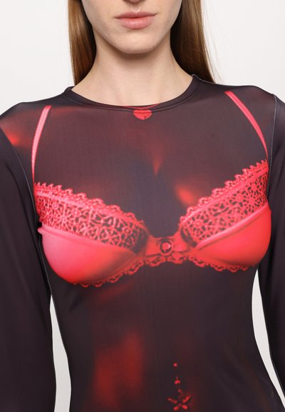 Long-sleeve top featuring a dark fabric with a vivid red lace-patterned bra print on the chest area; smooth texture and fitted design.