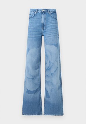 Jean bleu clair à jambes larges avec taille haute, bouton à l'avant et poches, présentant un motif floral subtil lavé sur les jambes.
