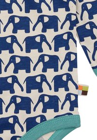 Langärmliger Bodysuit mit einem cremefarbenen Hintergrund und einem sich wiederholenden dunkelblauen Elefantenmotiv. Aqua-Finish an Hals- und Beinausschnitten hebt das Design hervor.