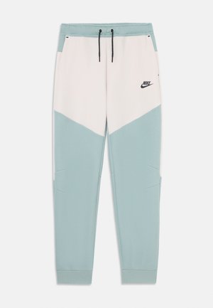Pantalons de survêtement Nike au design en chevron, composés d'un mélange de tissus doux, dans des couleurs bleu pâle et crème, avec une taille élastique et des poches latérales.