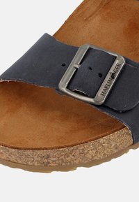 Mörkblå sandal med bred rem, justerbart silverfärgat spänne, korksula och fotbädd i tanmocka, med en naturlig textur.