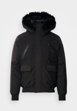 Zwarte geïsoleerde jack met een nepbont capuchon, ritszakken op de borst en zijflapzakken. Beschikt over elastische manchetten en een zoom voor een snug fit.