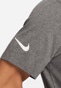 T-shirt grigio a maniche corte realizzato in tessuto morbido, con il logo swoosh bianco di Nike sulla manica sinistra.