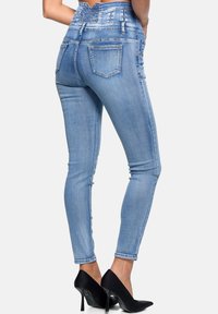 Jeans ajustados de color azul claro con una cinturilla alta, que cuentan con un mosaico texturizado en la parte posterior, dos bolsillos traseros y un acabado de denim suave.