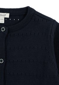 Marineblauer Strickcardigan mit rundem Ausschnitt, der vertikale Stickmuster und einen Knopfverschluss aufweist. Das Etikett zeigt die Größe 104 (3-4 Jahre).