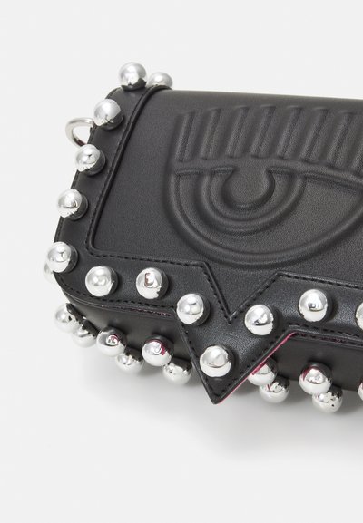 Black leather clutch with silver studs along the edges, featuring a raised eye design on the front and pink interior lining.