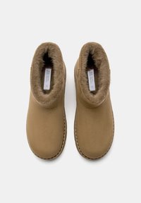 Hnedé členkové topánky so soft, kožušinou podšitou vnútornou časťou a hladkým vonkajším materiálom. Majú zaoblenú špičku a prešité detaily pozdĺž spodnej časti.