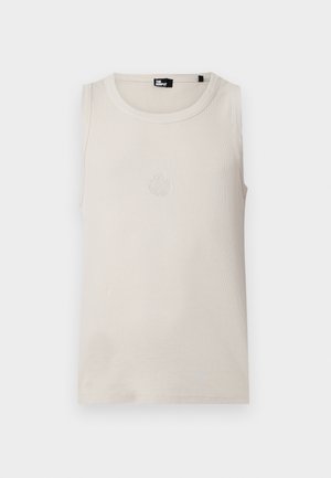 Bezrukavi bež top s rebrastim uzorkom, okruglim izrezom i suptilnim vezenim grbom u sredini prsa, s oznakom marke unutar ovratnika.