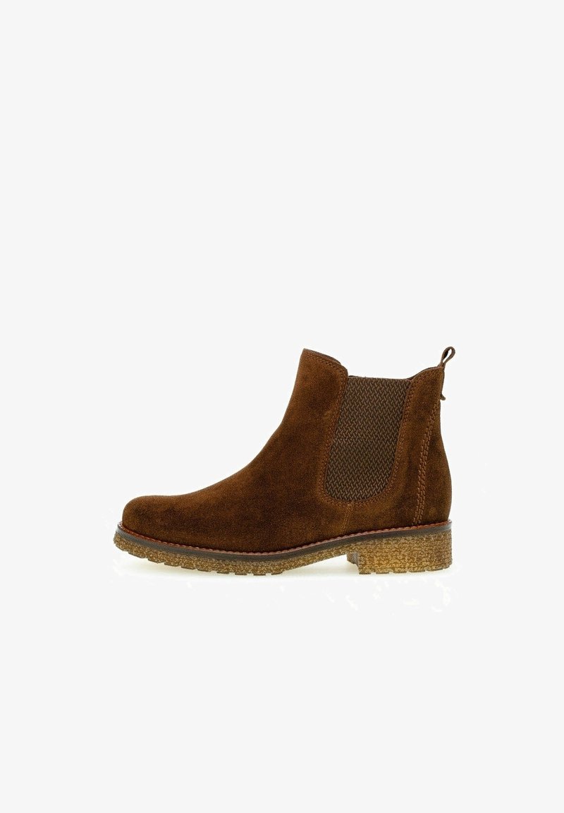 Stivaletto in suede marrone con pannelli elastici ai lati, punta rotonda e suola in gomma testurizzata per una migliore aderenza. Tacco basso e impilato.