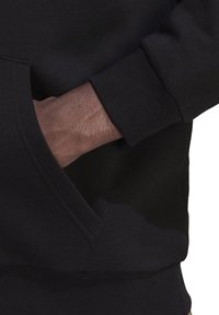 Felpa nera con tasca a marsupio, polsini a costine e tessuto testurizzato. Presenta una superficie morbida e liscia e cuciture eleganti.