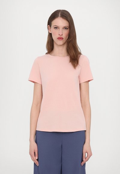 Light pink short-sleeve t-shirt with a round neckline, made of cotton. Simple, straight cut and smooth texture. Paired with navy blue pants.