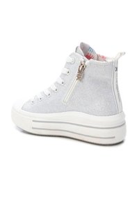 Zapatilla alta blanca hecha de lona texturizada, con una cremallera lateral, punta redonda y una gruesa suela de plataforma blanca con sutiles rayas grises.