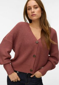 Violets krāsas tamborēts kardigans ar V-veida izgriezumu, ribveida aprocēm un trim lieliem pogām priekšpusē, ar vaļīgu piegriezumu un teksturētu rakstu.