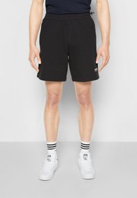 Pantaloni corti neri in cotone con elastico in vita e cordoncino, dotati di tasche laterali e un piccolo logo rosso sulla coscia.