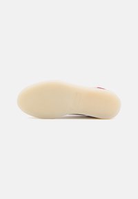 Semelle de chaussure avec une semelle inférieure beige lisse et translucide, présentée à plat sur un fond blanc uni.