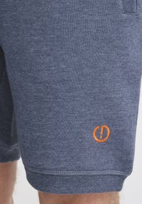 Marineblå bomuldsshorts med en tekstureret overflade, der har et broderet orange logo nederst og en tætsiddende talje.