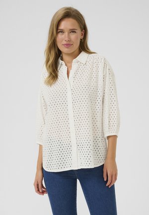 Weißes, button-down Hemd aus perforiertem Material mit Kragen und Dreiviertelärmeln. Texturiert mit kleinen Löchern über das gesamte Hemd.