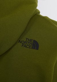 Bluza z kapturem w oliwkowej zieleni; na piersi haftowane czarne logo "THE NORTH FACE". Gładka faktura, casualowy design.
