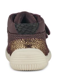 Zapatilla púrpura con parte superior de malla texturizada, acentos con manchas doradas y un patrón de piel de serpiente negra en el talón. Suela de goma blanca.