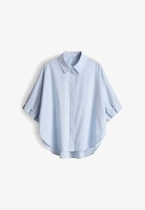 Hellblaue Bluse mit kurzen Ärmeln, spitzem Kragen, durchgehender Knopfleiste und leicht abgerundetem Saum, die vor weißem Hintergrund hängt.