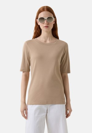 Beige tričko s krátkým rukávem vyrobené z měkké látky, s kulatým výstřihem a slim fit střihem, doplněné šedými slunečními brýlemi.