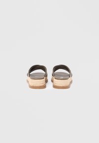 Sandale maro cu barete și talpă espadrile împletită, având o talpă netedă și un design minimalist. Vedere din spate cu barete curbate și accente texturate.