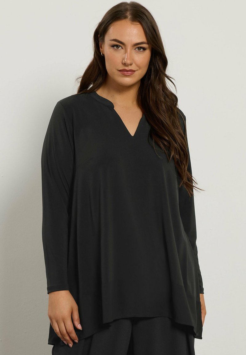 Top lungo nero a maniche lunghe con scollatura a V, caratterizzato da una vestibilità ampia e una texture liscia. Il design si allunga leggermente all'orlo.