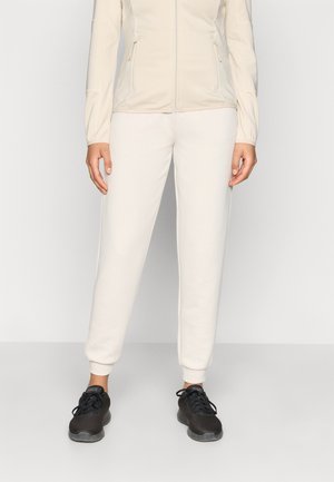 Φωτεινό μπεζ μπουφάν με φερμουάρ και υφασμένα μανίκια, συνδυασμένο με κρεμ παντελόνι jogger και μαύρα αθλητικά παπούτσια από δίχτυ. Απλή και λειτουργική αθλητική ενδυμασία.