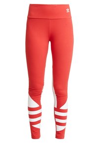 Röda tajta leggings i stretchmaterial med hög midja och vita diagonala ränder på båda benen för kontrast.