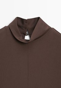 Haut marron à col montant imitation, en tissu lisse et extensible, avec fermeture par bouton dans le dos et design sans coutures. Look simple et minimaliste.