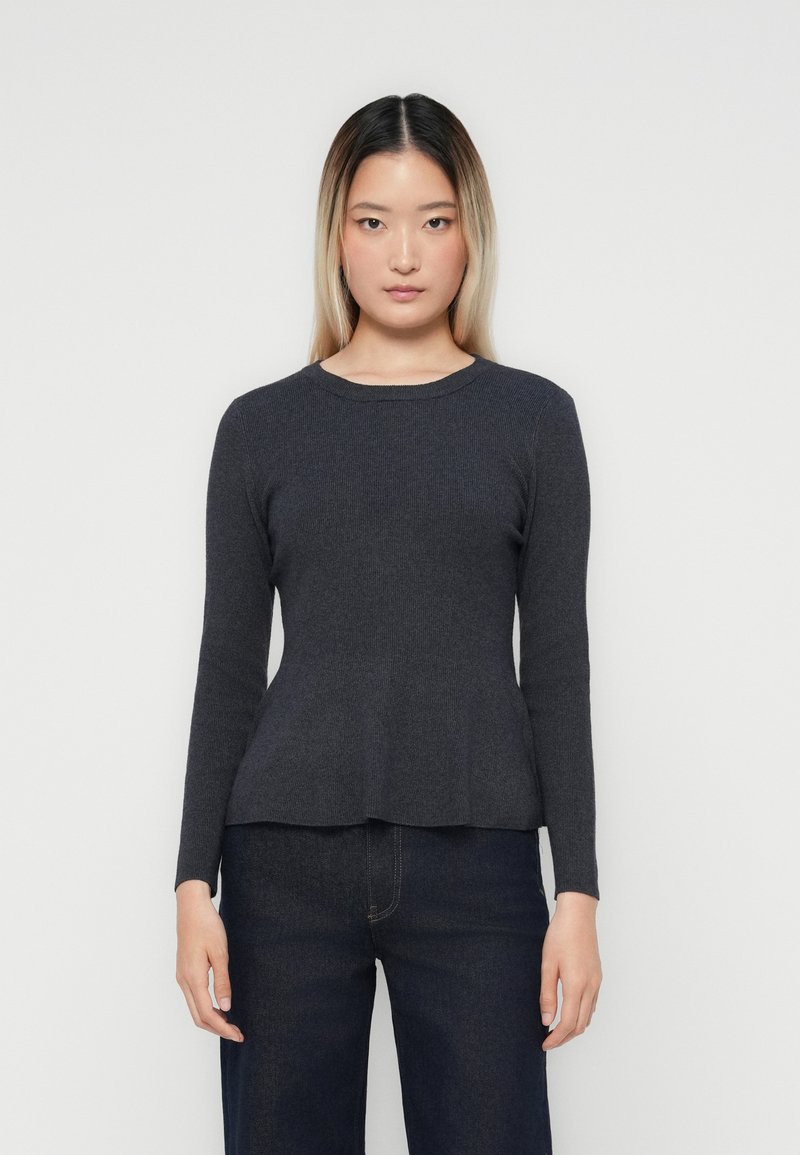 Pull long gris foncé à manches longues avec un col rond, texture côtelée et ourlet à peplum, associé à un jean foncé. Design minimaliste.