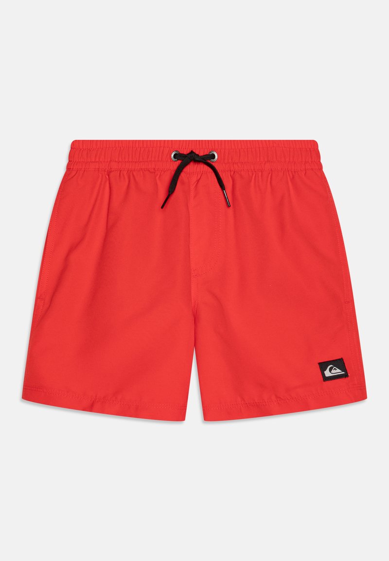 Red swim shorts with an elastic waistband, black drawstring, and a small black logo patch on the front left side. Smooth texture.