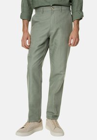 Lichtgroene katoenen broek met een rechte pasvorm, voorzien van een rits en knoopsluiting. Gecombineerd met beige sneakers. Minimalistisch ontwerp.