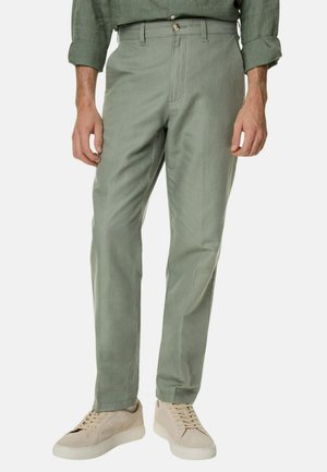 Lichtgroene katoenen broek met een rechte pasvorm, voorzien van een rits en knoopsluiting. Gecombineerd met beige sneakers. Minimalistisch ontwerp.