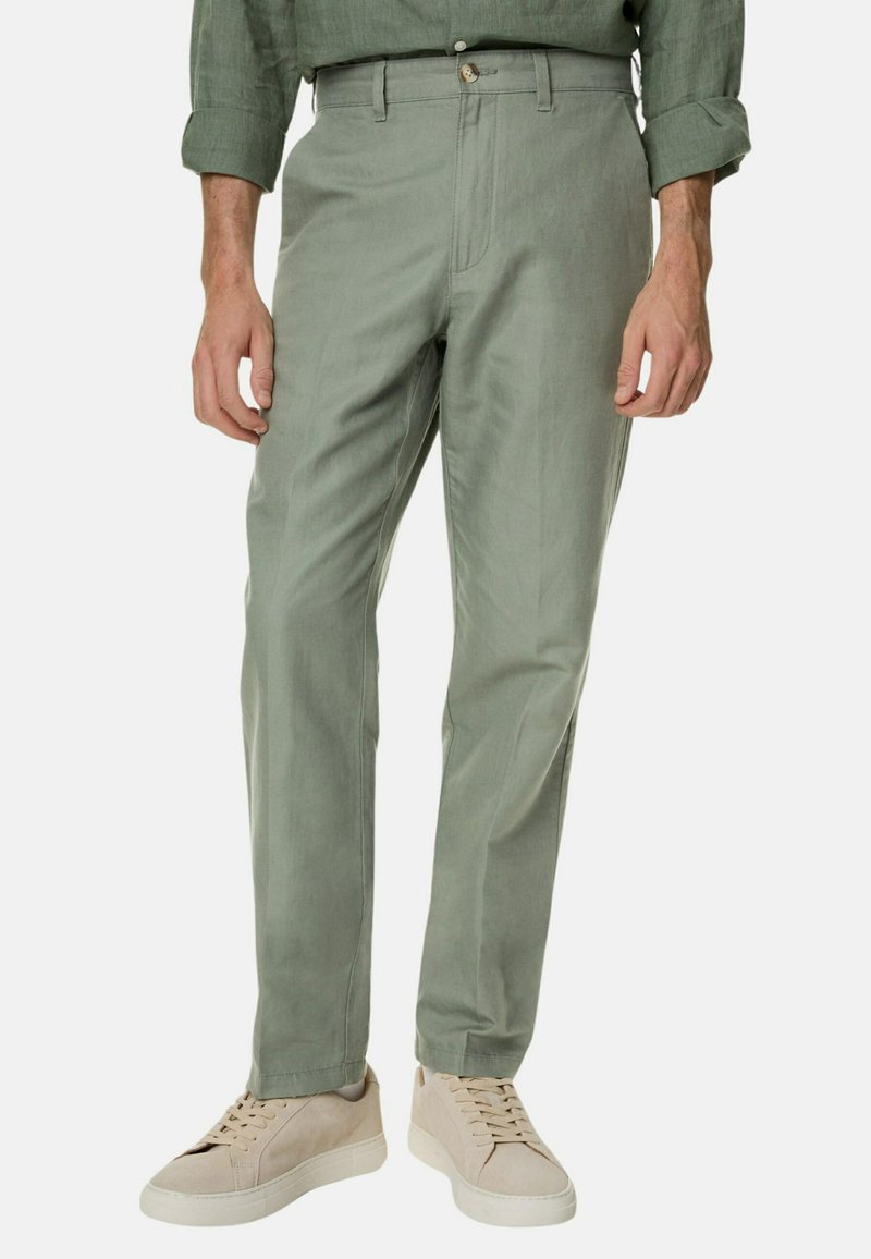 Lichtgroene katoenen broek met een rechte pasvorm, voorzien van een rits en knoopsluiting. Gecombineerd met beige sneakers. Minimalistisch ontwerp.