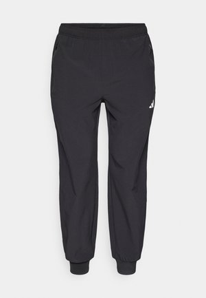 Schwarze Sporthose mit elastischem Bund, zwei seitlichen Reißverschlusstaschen, zulaufenden Beinenden und einem kleinen weißen Logo am oberen linken Oberschenkel.