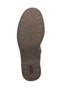 Semelle en caoutchouc brun avec un motif de traction texturé, comprenant des crampons et des sections de grip, conçue pour l'adhérence et la durabilité.