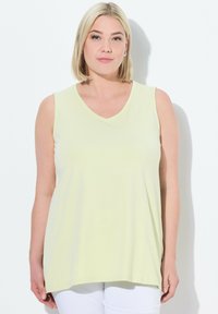 Top senza maniche di un leggero giallo chiaro, realizzato in tessuto morbido, caratterizzato da una vestibilità rilassata e una superficie liscia, con orlo che scende sotto i fianchi.