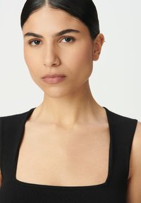 Top negro sin mangas con escote cuadrado, que presenta una textura suave y un diseño ajustado. El modelo tiene el cabello negro lacio.